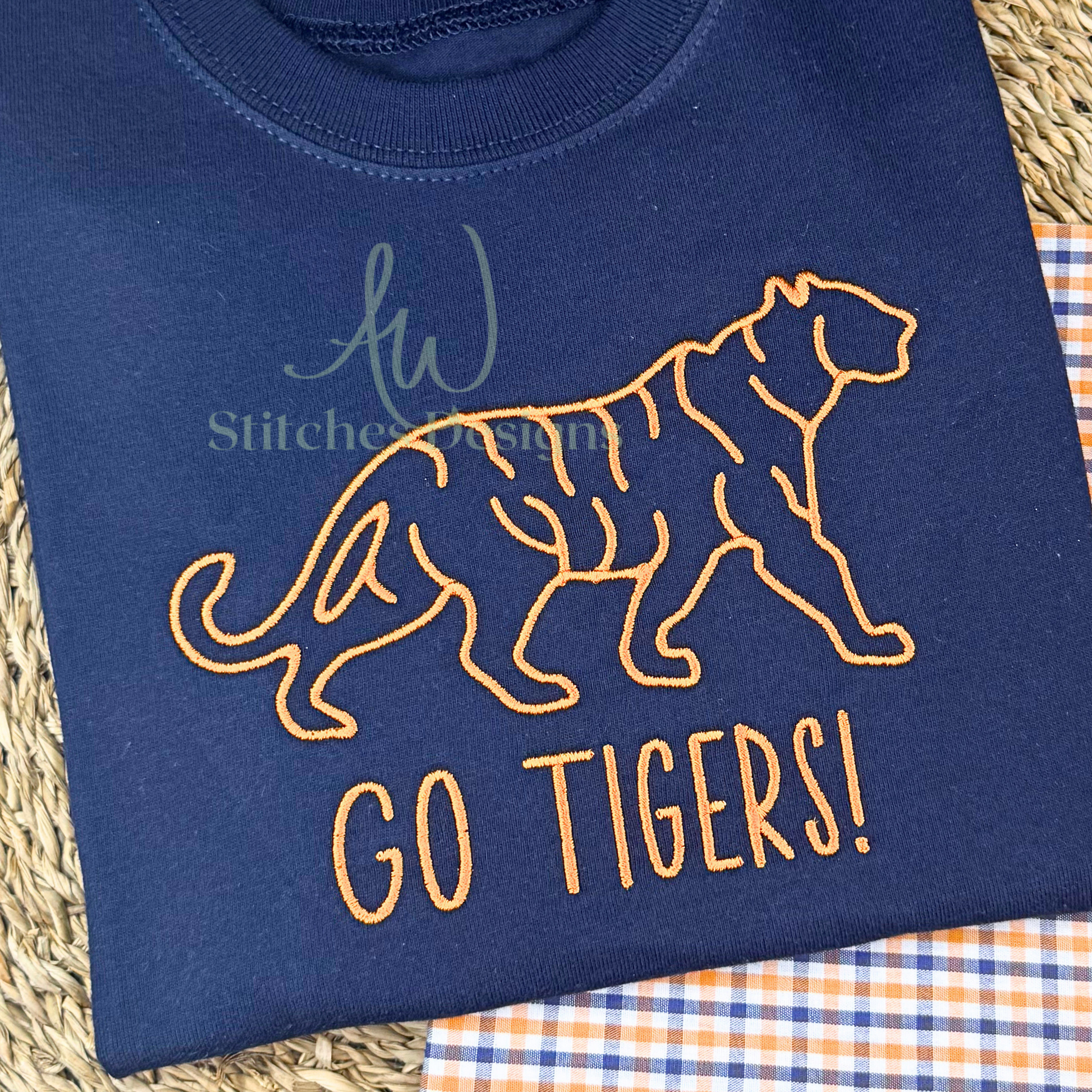 Close-up of orange satin stitch tiger embroidery on navy cotton shirt