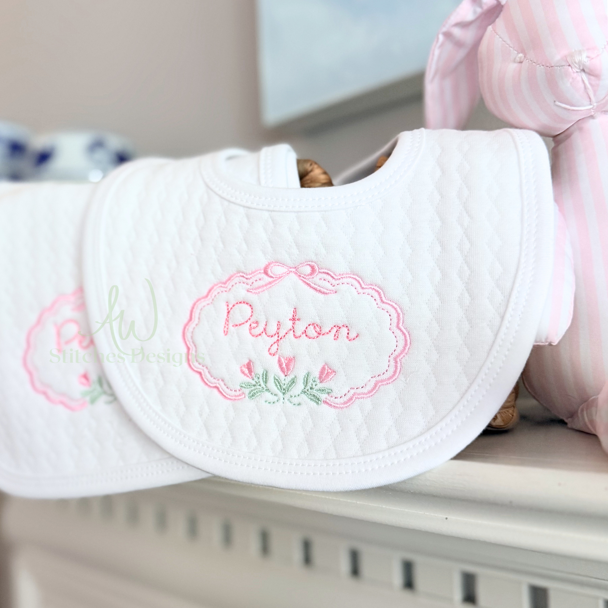 White baby bib with embroidered name 'Peyton' on a shelf.