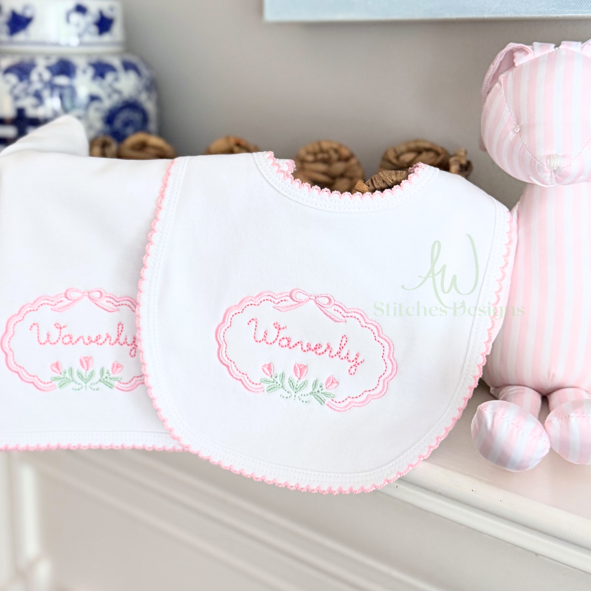White bib with pink embroidery on a shelf with decorative items