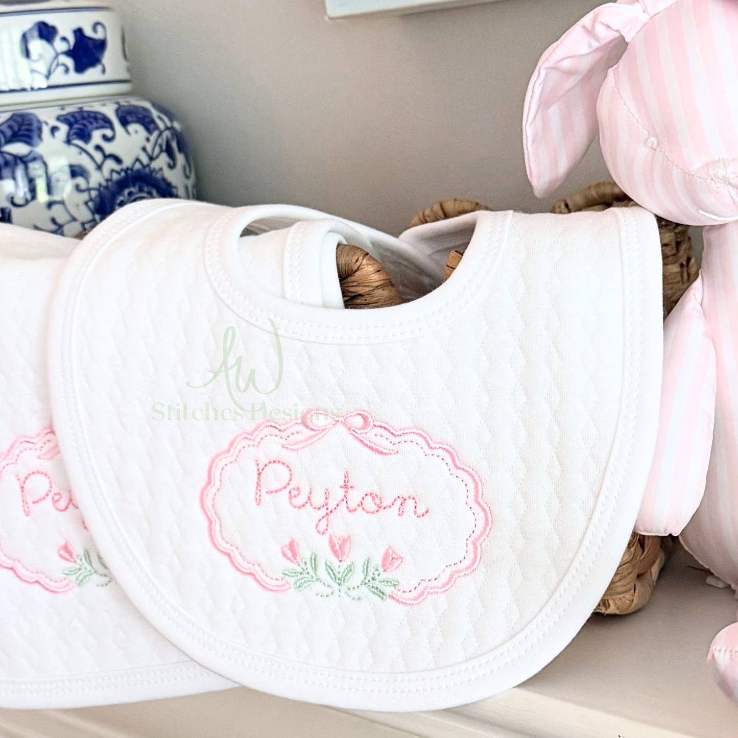 White bib with embroidered name 'Peyton' on a shelf with decorative items.