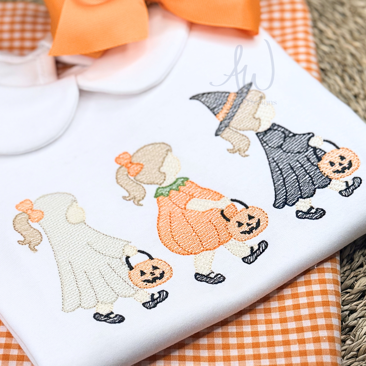 Embroidered design on a white fabric with Halloween-themed characters including ghosts, pumpkins, and witches.