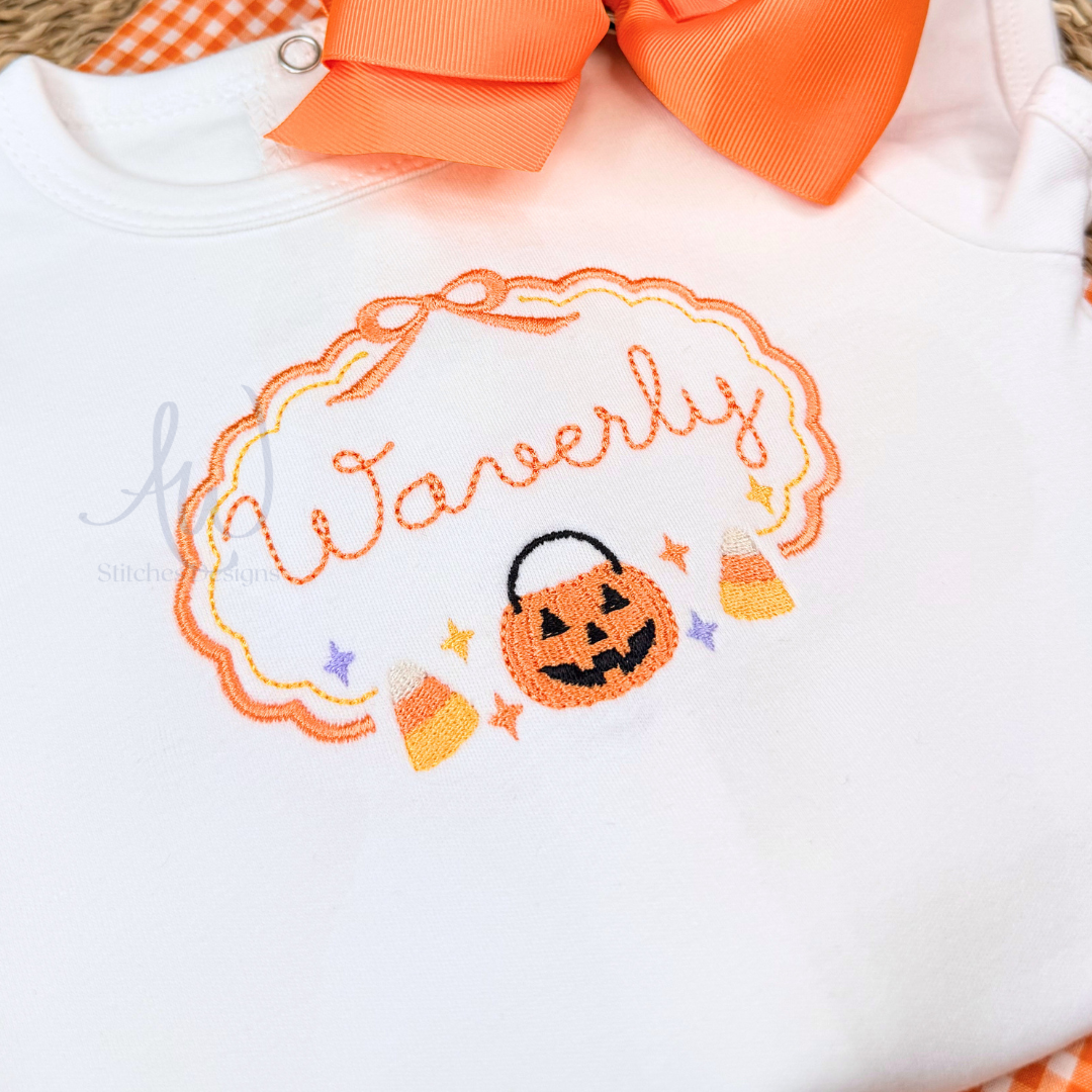 A white baby bodysuit featuring a personalized Halloween embroidery design with the name 'Warnerly' in orange script inside an orange pumpkin-shaped frame, complete with a jack-o'-lantern, candy corn, and stars. The bodysuit is styled with an orange ribbon bow at the neckline.