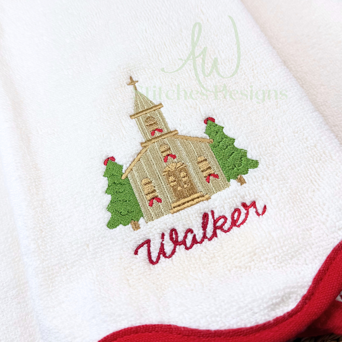 Mini Christmas church embroidery design stitched on a white hand towel with evergreen trees and red holiday accents