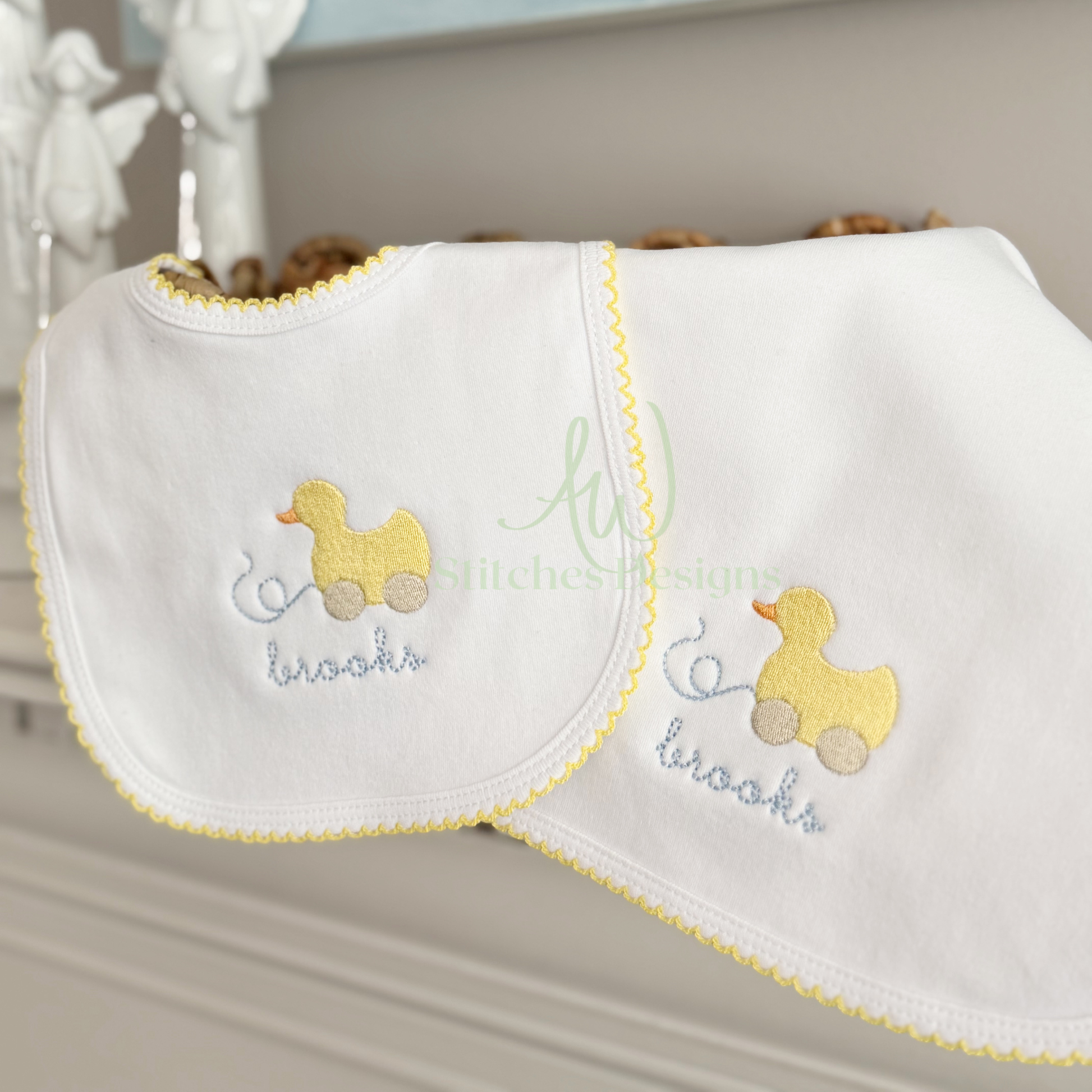 Two baby bibs with duck designs and embroidered names on a neutral background