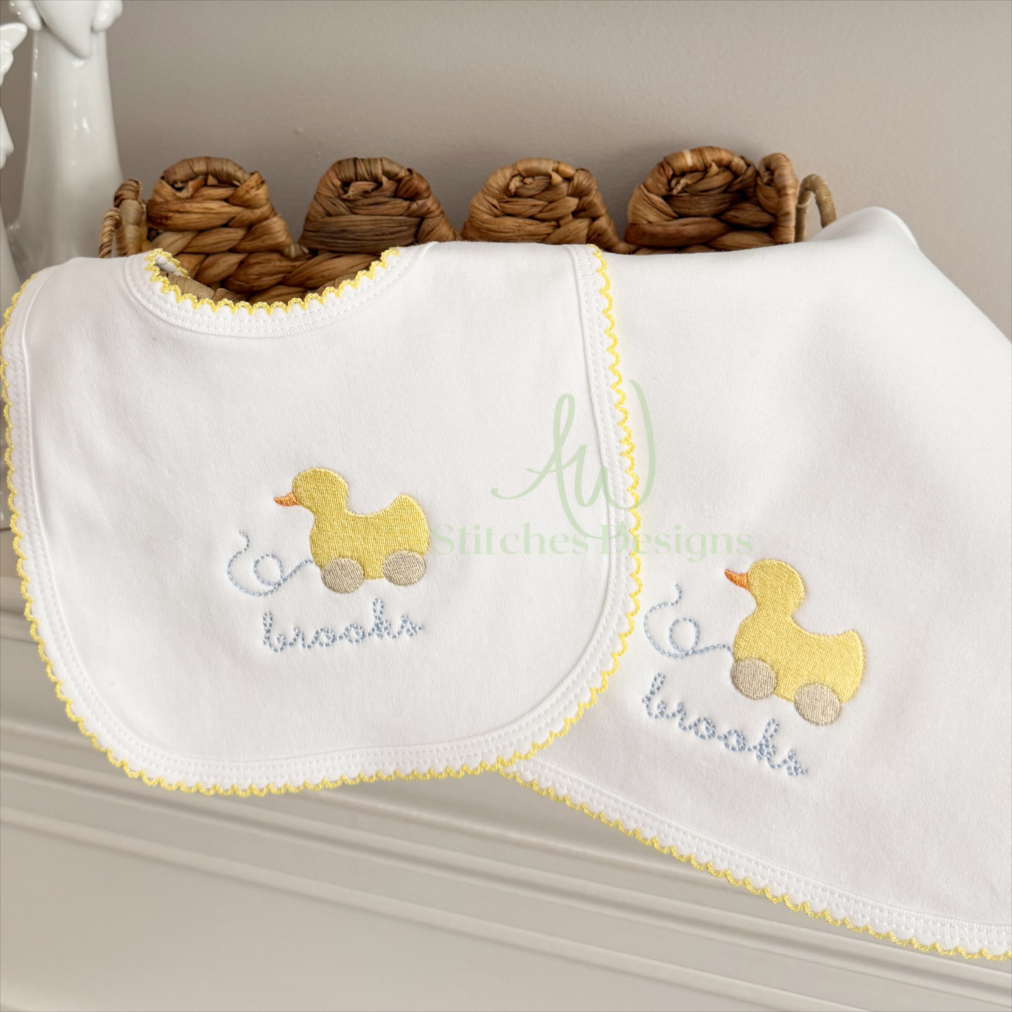 White bib with embroidered yellow duck and text on a neutral background