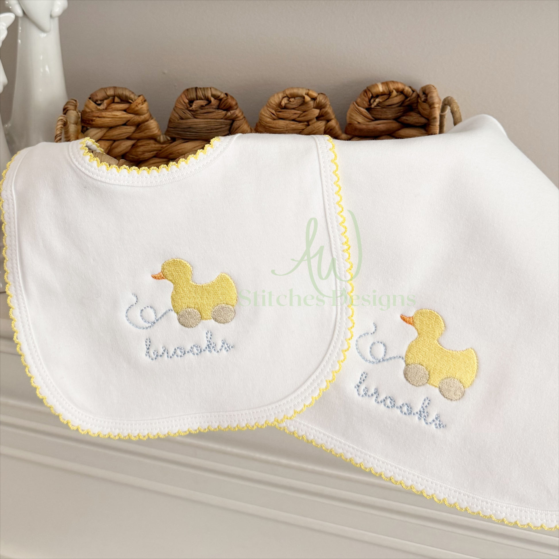 White bib with embroidered yellow duck and text on a neutral background