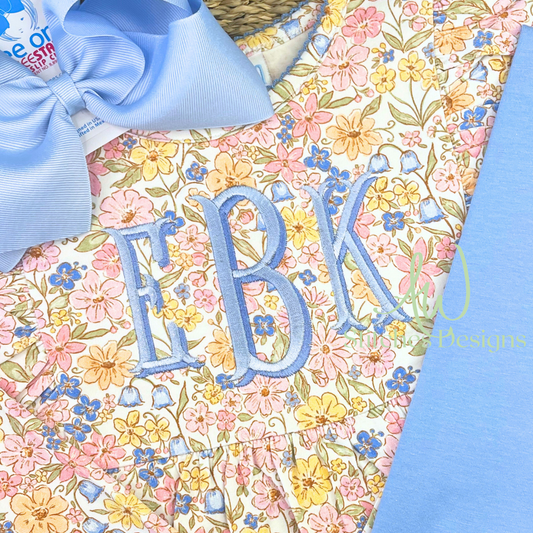 Shadow fishtail monogram satin stitch embroidery font stitched in blue on a floral dress with bow, machine embroidery design file with BX by AW Stitches Designs