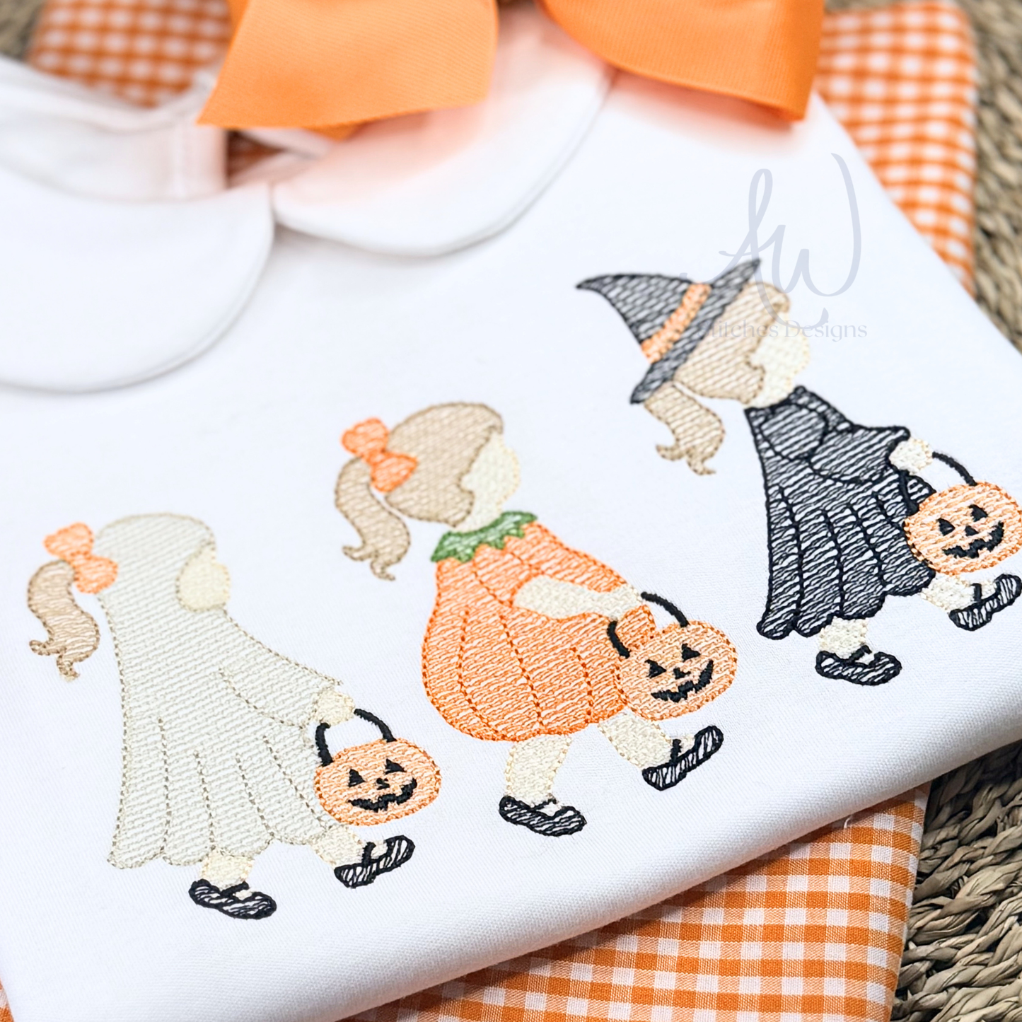 Embroidered design of Halloween-themed characters on a white fabric background.