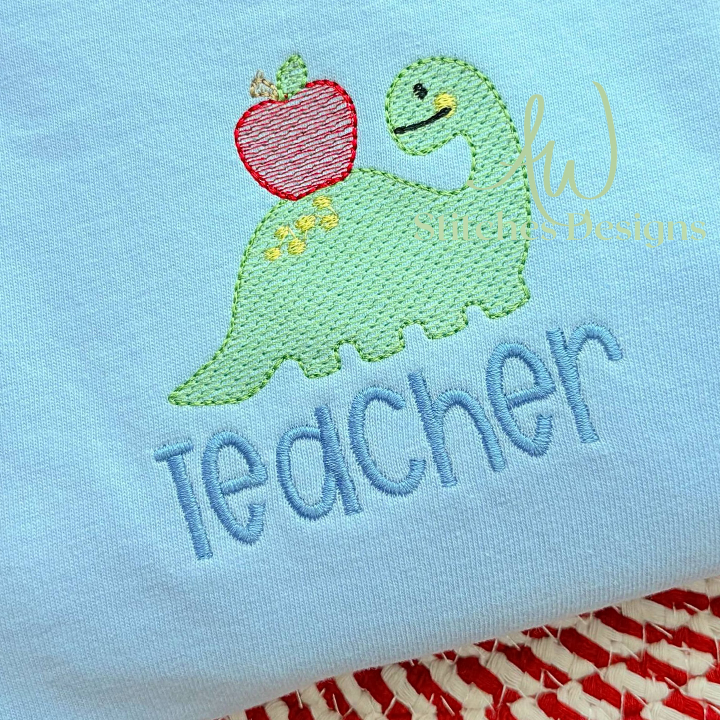 Embroidered dinosaur holding an apple with 'teacher' text on a light blue background