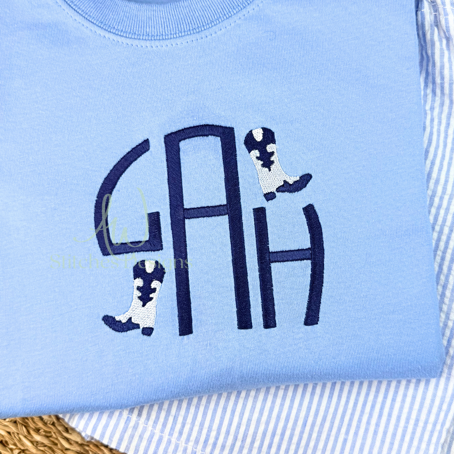 Light blue sweatshirt with navy monogram and cowboy boot designs on a striped background