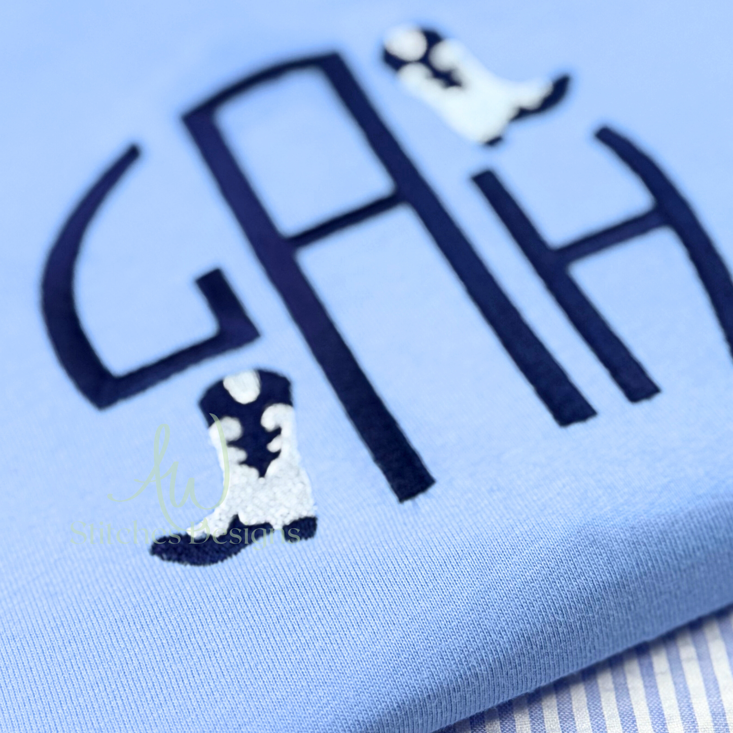 Light blue fabric with embroidered name and boot designs on a light blue background