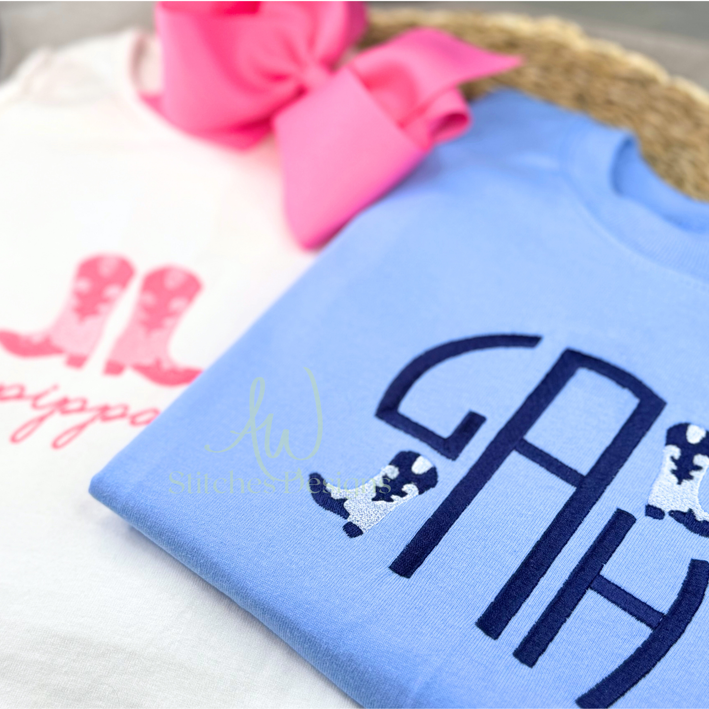 Light blue shirt with monogram design on a white surface with pink hair bow